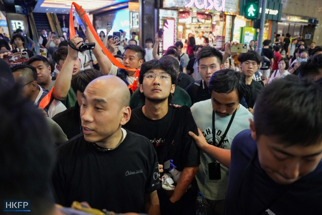 A young man in a black T-shirt is intercepted by police on June 4, 2026. Photo: Kyle Lam/HKFP.