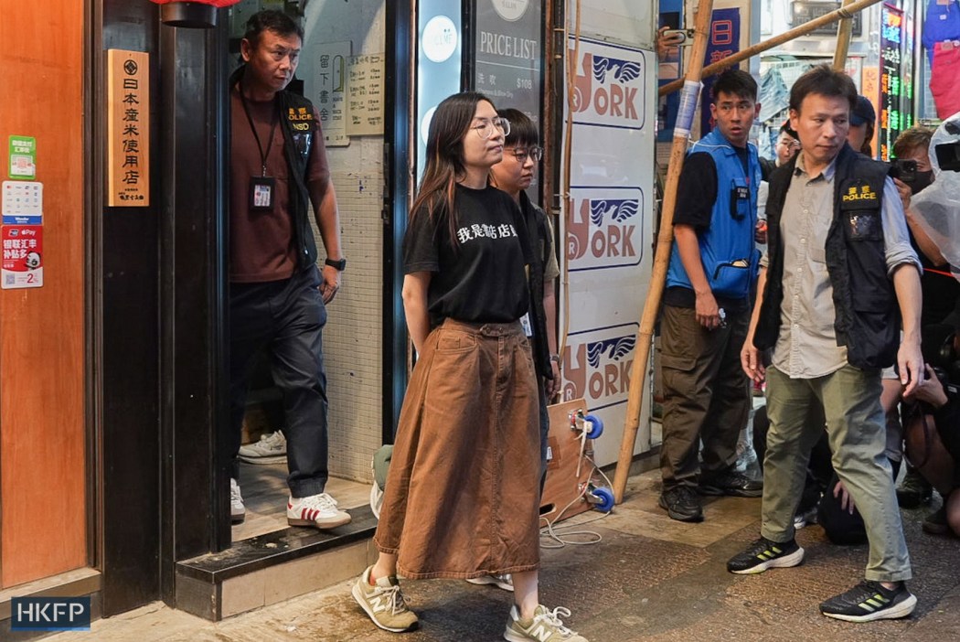 A woman is taken away from indie bookstore Have a Nice Stay, escorted by police, on July 15, 2026. Photo: Kyle Lam/HKFP.