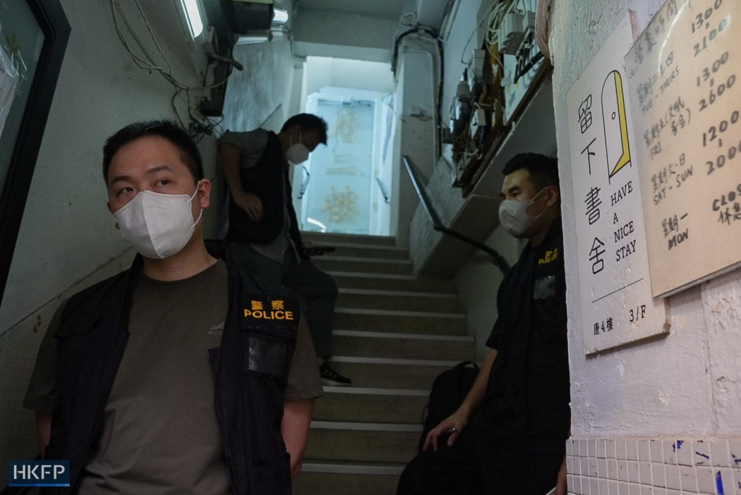 Police officers at the entrance of the building of Have a Nice Stay, on July 15, 2026. Photo: Kyle Lam/HKFP.