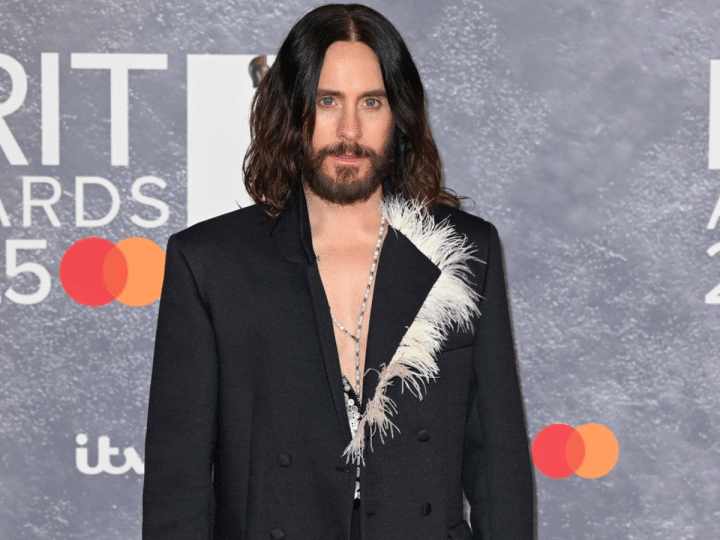 Jared Leto in a suit blazer with his bare chest exposed at the top, posing infront of Brit Award backdrop. Year unknown.