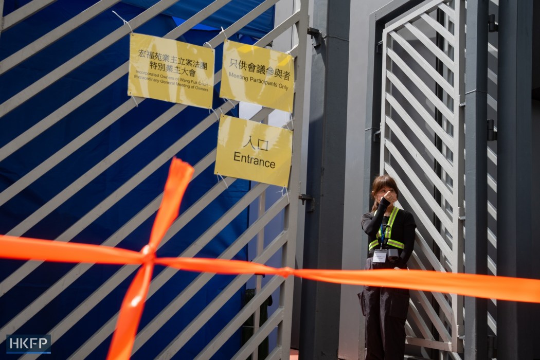 A staff guards the entrance as Wang Fuk Court residents attend a flat owners meeting at Tai Po Community Centre on July 19, 2026. Photo: Kyle Lam/HKFP.