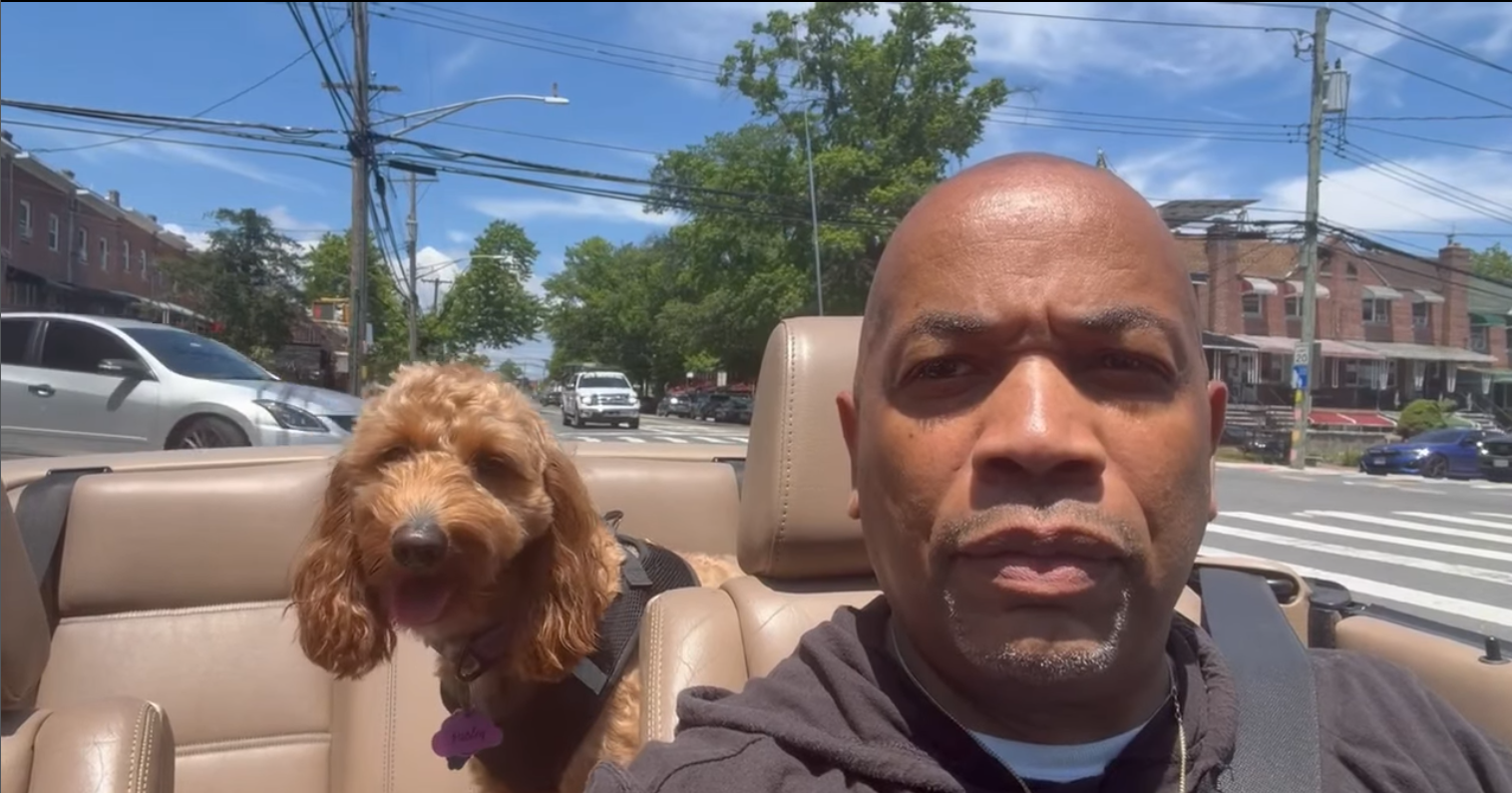 A man scowls in a convertible with his doodle.