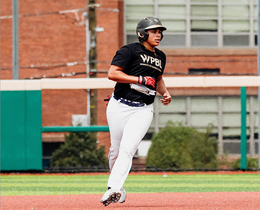 A woman in a black uniform runs the bases on a baseball diamond.