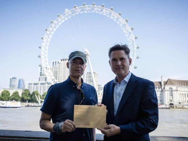MPs Clive Lewis and Charlie Maynard in front of the Thames and London Eye, holding an open letter concerning Thames Water