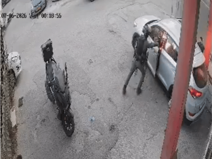 Screenshot of CCTV footage showing an Israeli officer pushing his weight against the car door and inside the vehicle is lit up orange as the grenade has exploded.