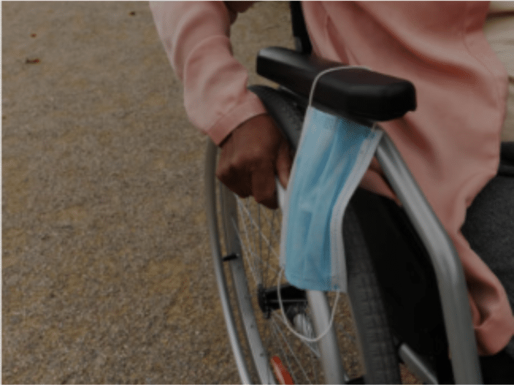 Close-up of the hand of a black woman pushing her wheelchair, she put her surgical face mask on the armrest. Police have warned unwell campaigners their health is not an automatic pass for wearing a face mask.