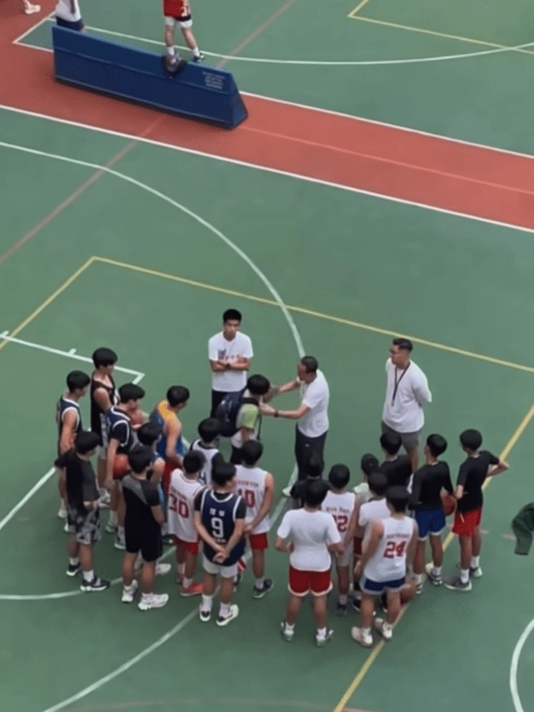 Screenshot of an online video shows basketball coach Yung Kam-wah slapping a student on a school court.