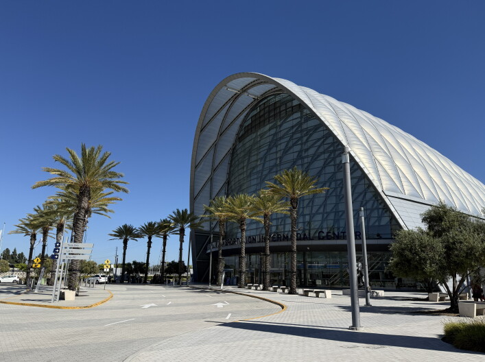 Exterior of the domed ARTIC train station, with palm trees outside under a bright blue sky.