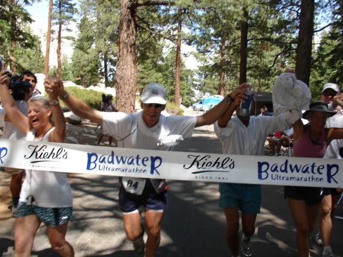 A group of people holding hands as they approach the finish line of a race