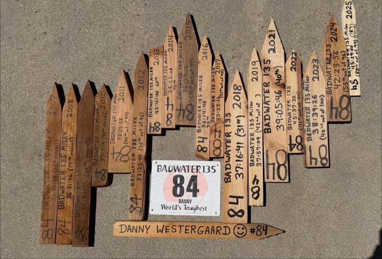 A bunch of wooden stakes with numbers and distance on each