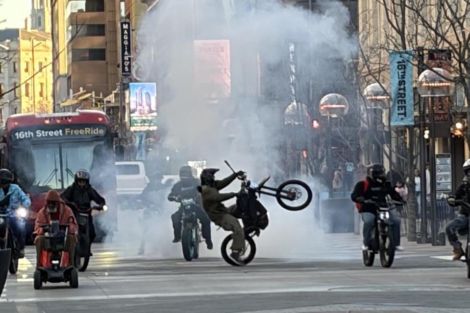 Dirt bike riders perform tricks and spew smoke on 16th Street in downtown Denver on March 8, 2026.