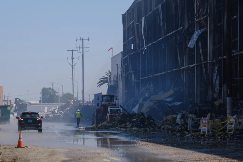 Crews clean up debris from a burned building.
