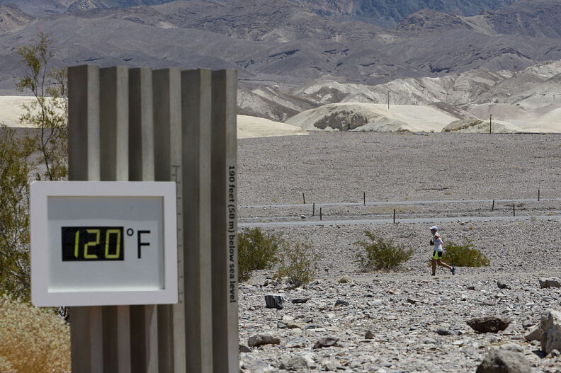 A thermometer shows 120 degrees in the foreground, as a runner runs across a desert landscape in the background.