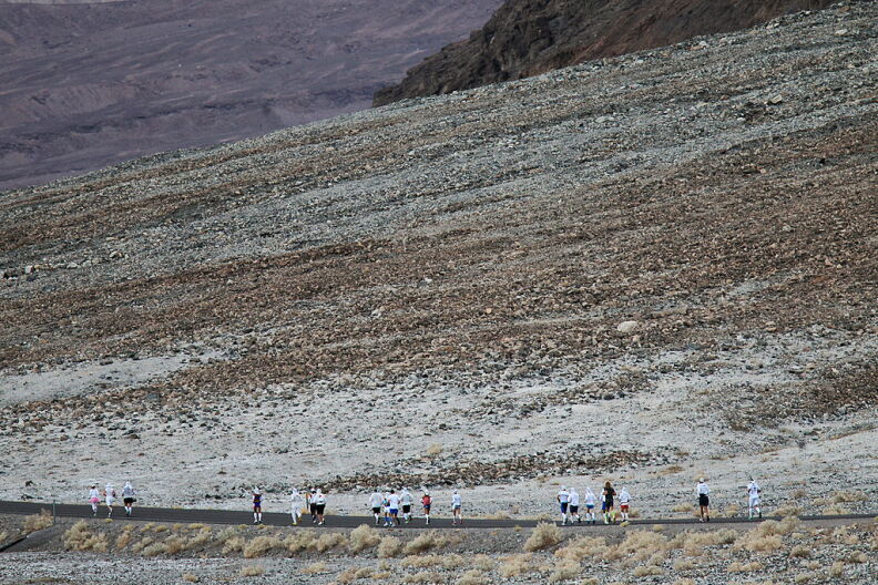 A line of runners running against a severe landscape of a desert