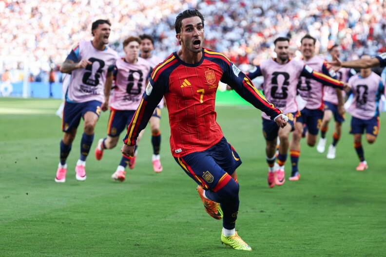 A man in a red soccer jersey runs down a field.