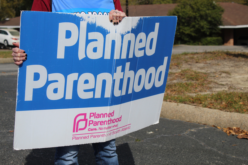 A volunteer clinic escort holds a sign outside a Planned Parenthood clinic in Columbia, South Carolina, on March 28, 2025. (Photo by Skylar Laird/SC Daily Gazette)