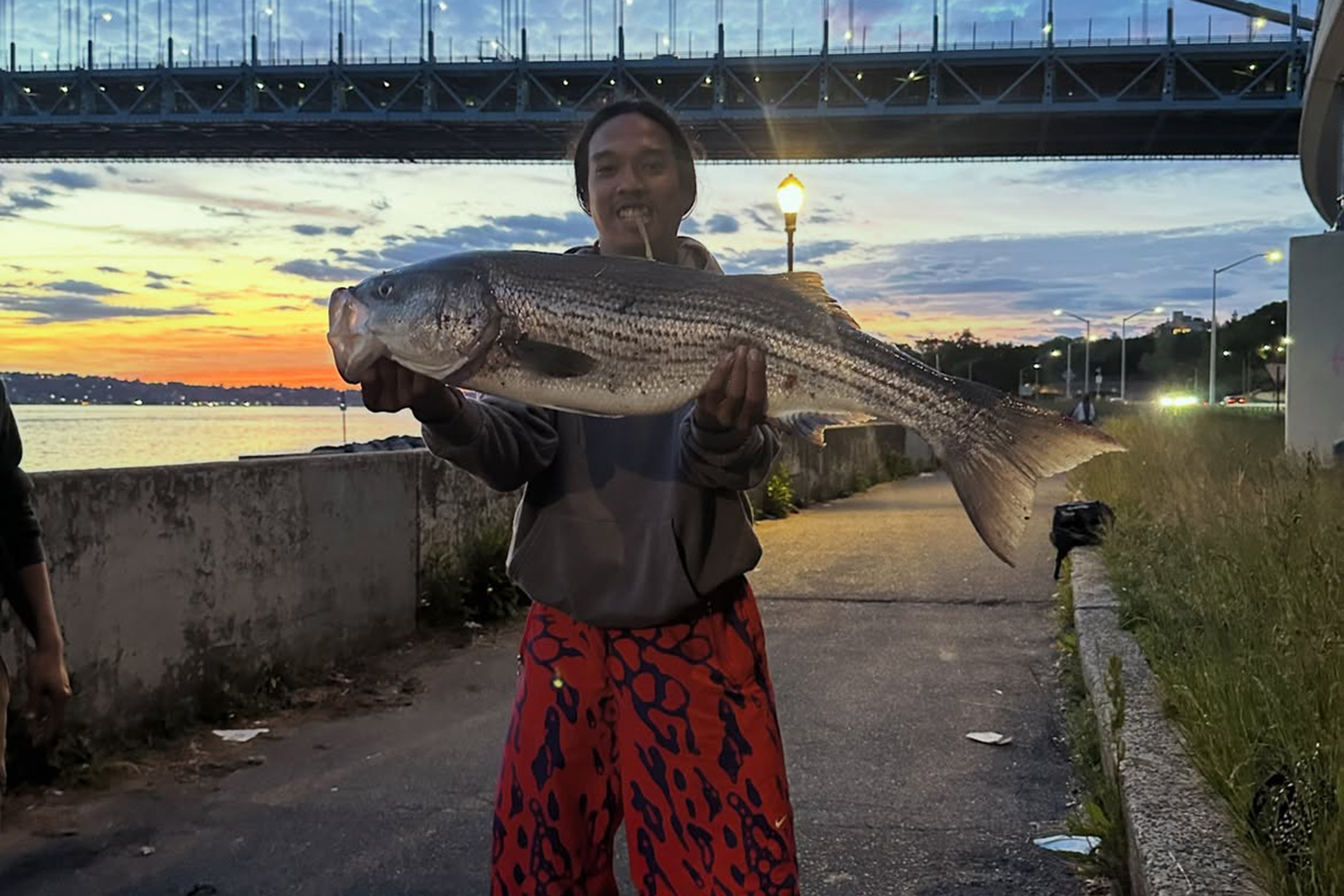 Joey Vatthanavong shows off a proud striped bass catch.
