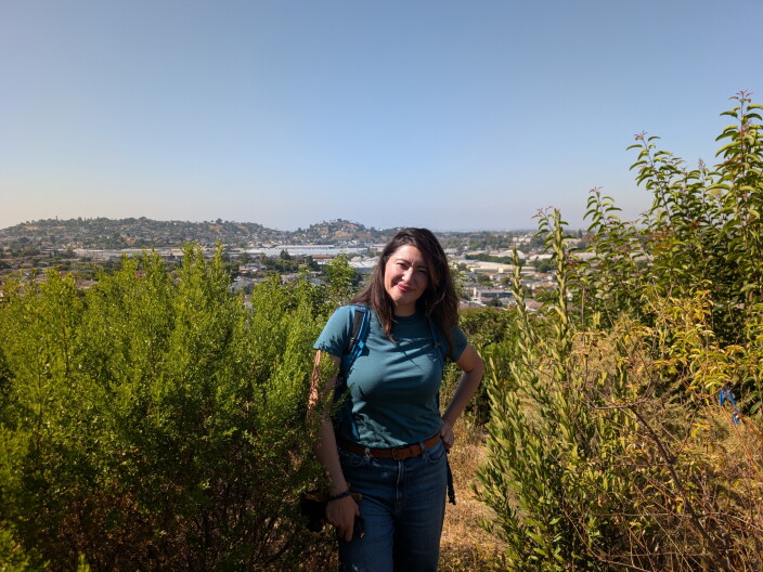 A woman in long brown hair standing next to a lot of native plants.