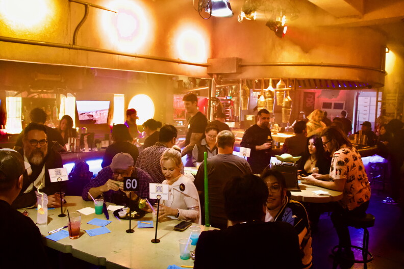 An interior of a bar showing lots of people sitting at tables. The atmosphere is fun and lively, with happy faces all around.