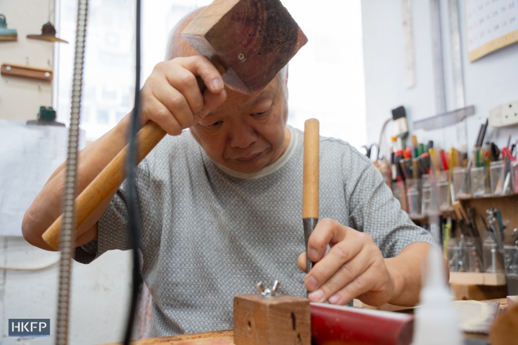 Vitus Siu using hammer and chisel crafting in an industrial building in Kwai Chung, July 27th, 2026. Photo: Kyle Lam/HKFP.