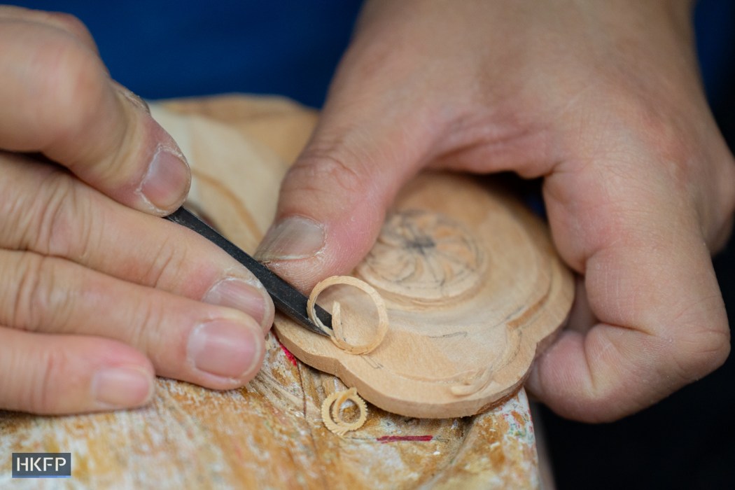 Vitus Siu use a knife carving on a wooden statue in an industrial building in Kwai Chung, April 8th, 2026. Photo: Kyle Lam/HKFP.
