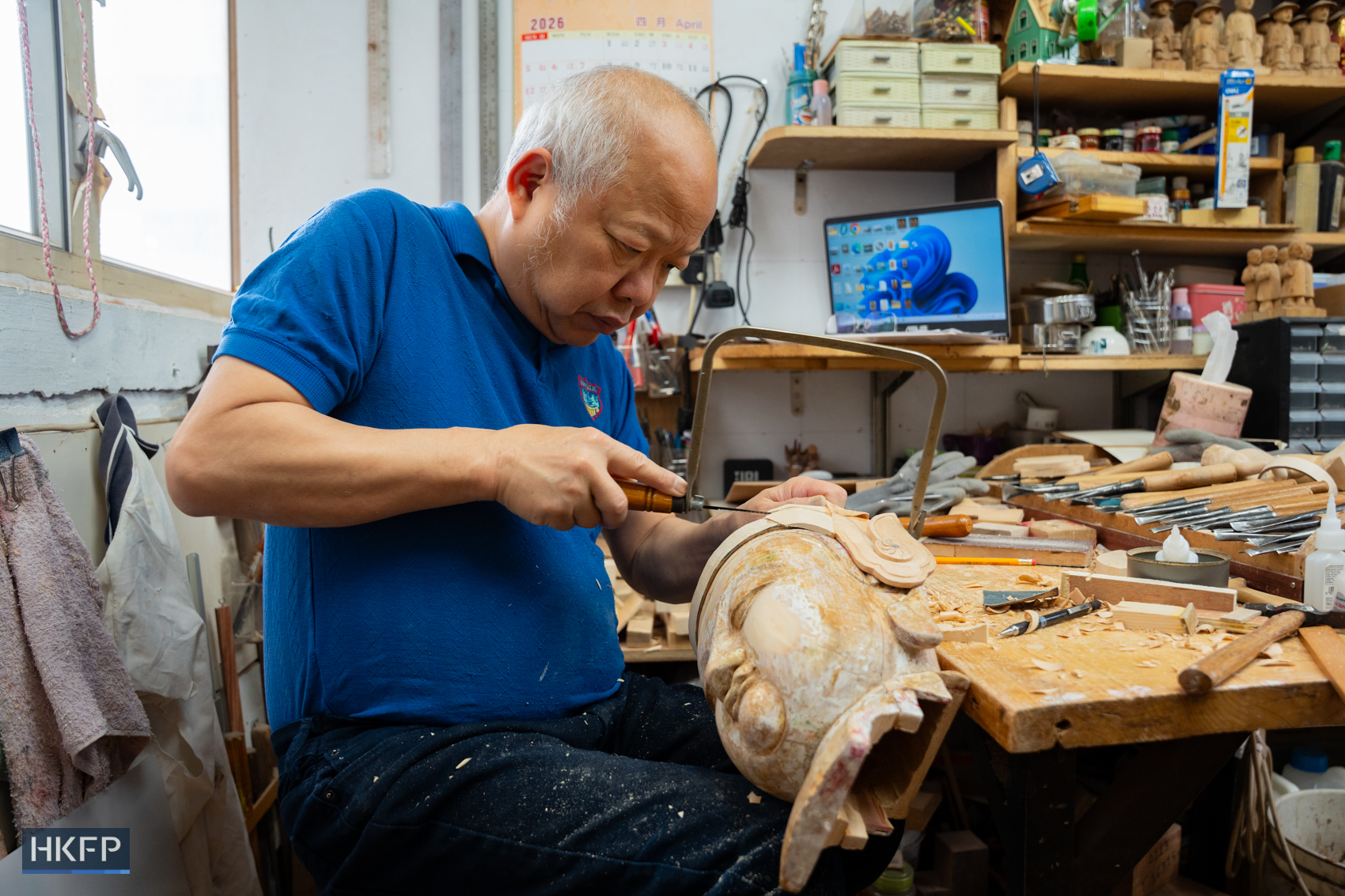 Vitus Siu use a saw carving on a wooden statue in an industrial building in Kwai Chung, April 8th, 2026. Photo: Kyle Lam/HKFP.