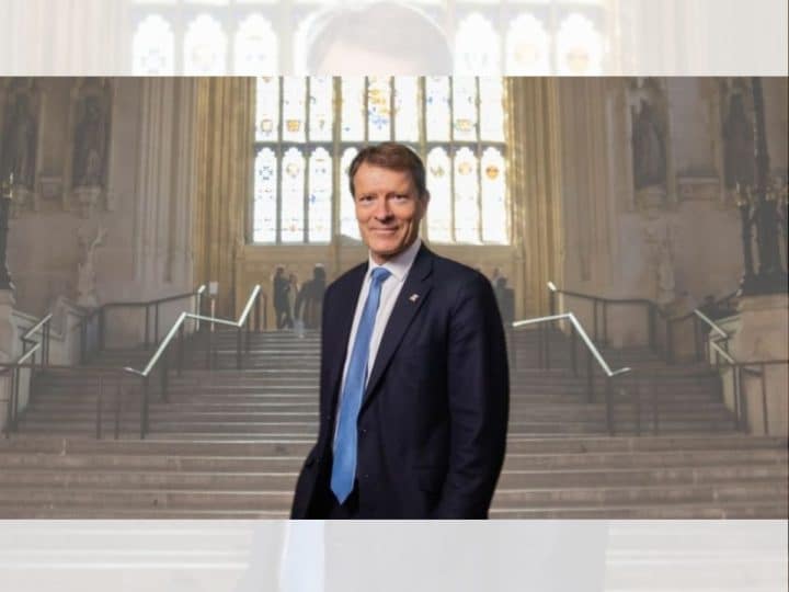 Richard Tice of Reform UK photographed on the Parliament estate in a large open room with steps and a large window behind him