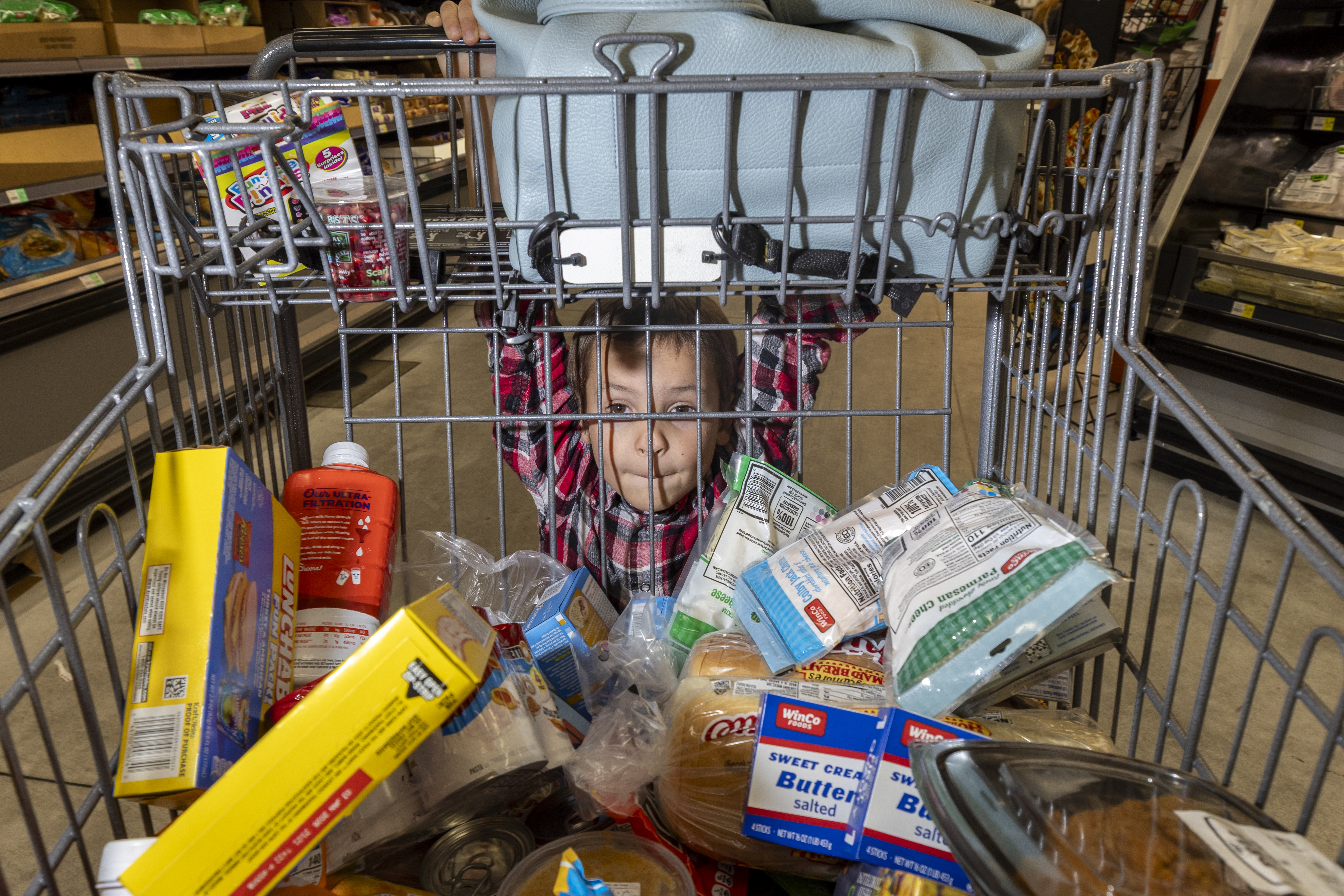 A child hanging off a shopping cart.