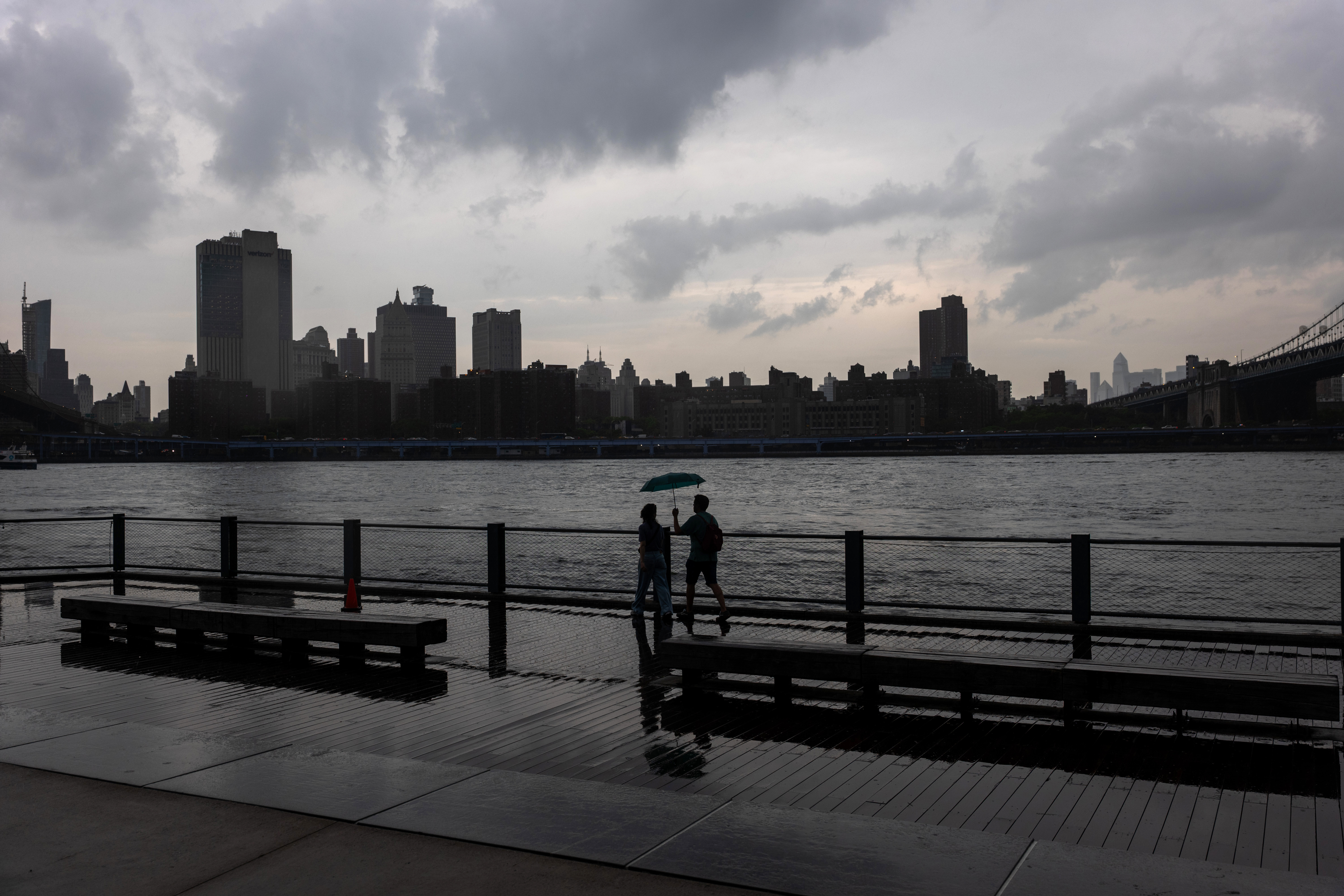 People walk through the rain in the Dumbo neighborhood in Brooklyn as severe storms move through the New York area on July 21, 2026 in New York City.