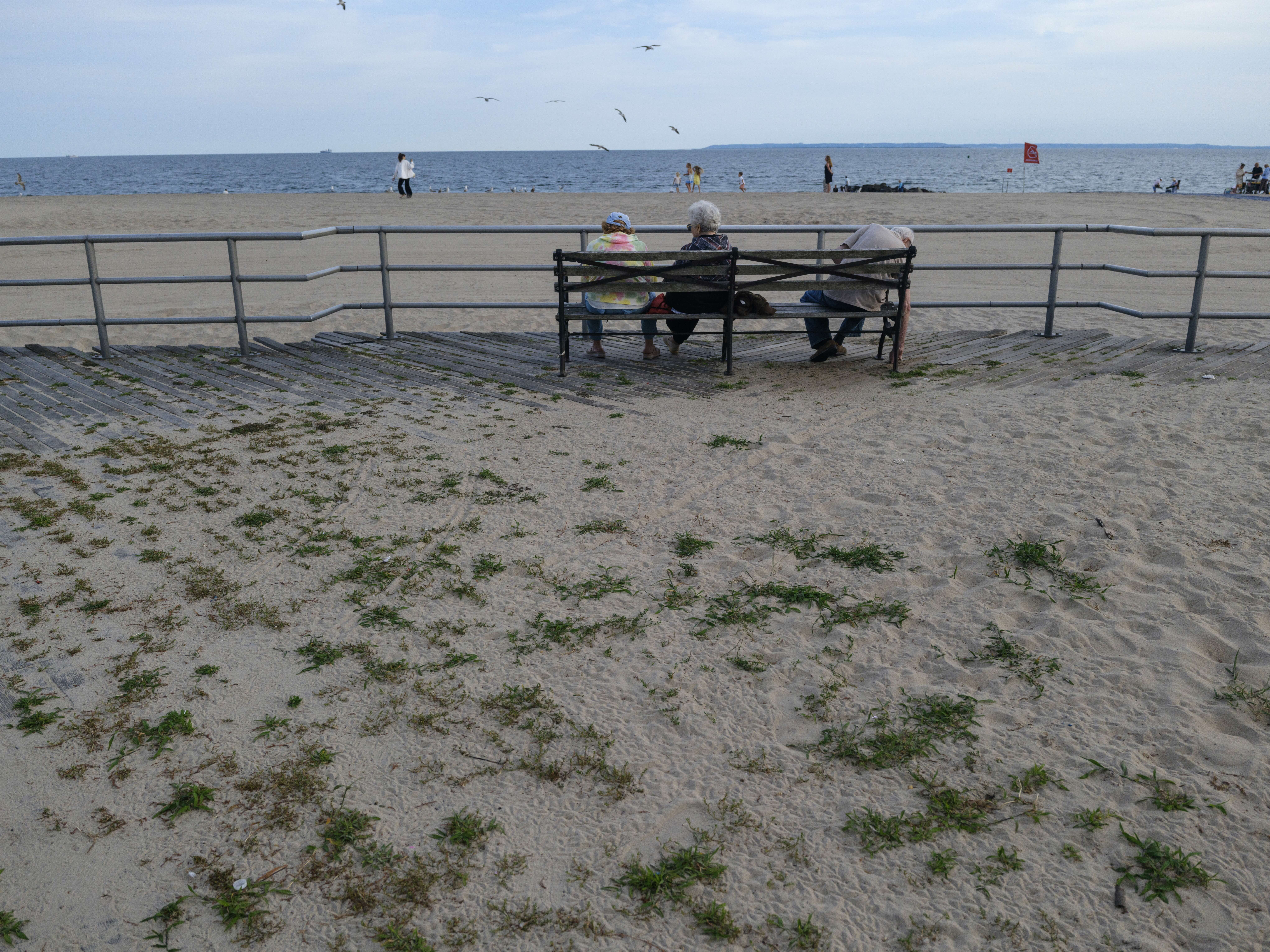 People sit on a boardwalk bench on July 24, 2026, in Coney Island.