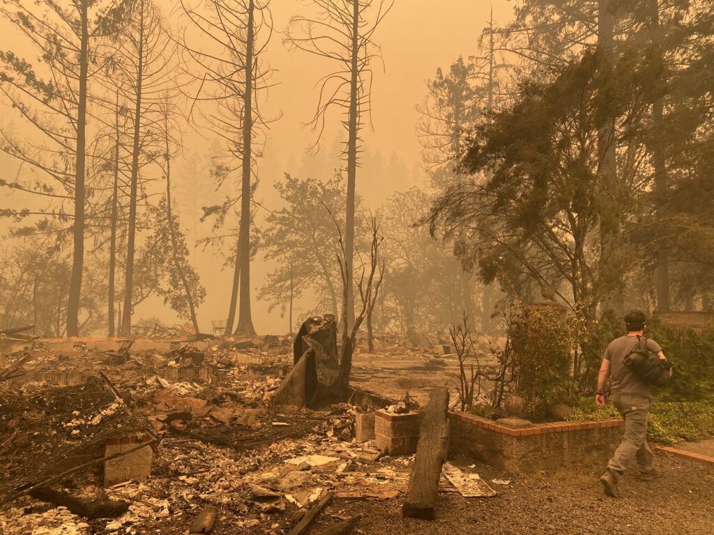 Sam Drevo stands next to the burned foundation of his mother's home in Gates following the 2020 Labor Day fires.