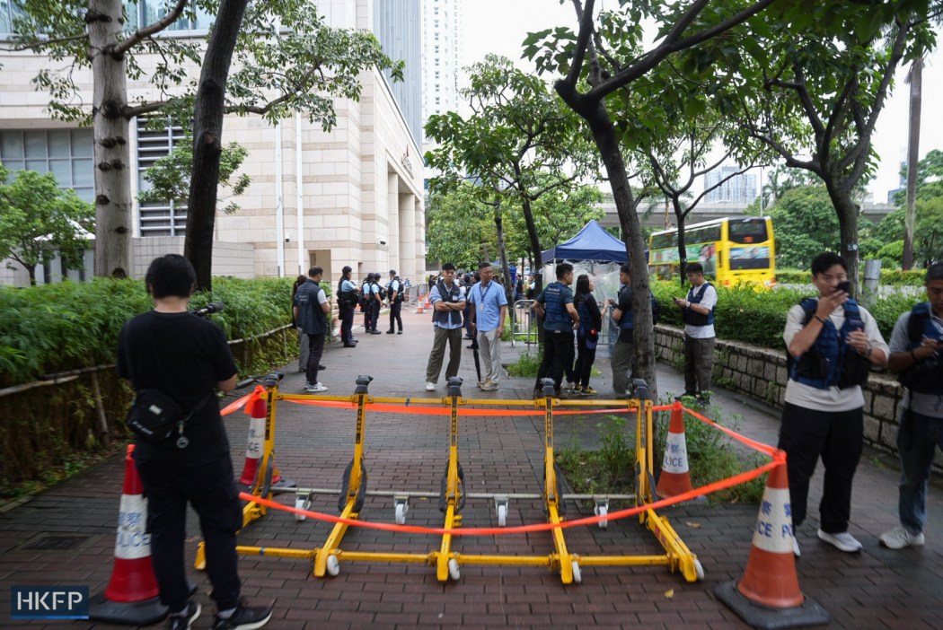Hong Kong police set up a cordon outside the West Kowloon Law Courts Building on August 21, 2026, ahead of the verdict hearing of the trial of two Tiananmen vigil activists Chow Hang-tang and Lee Cheuk-yan on national security charges. Photo: Kyle Lam/HKFP.