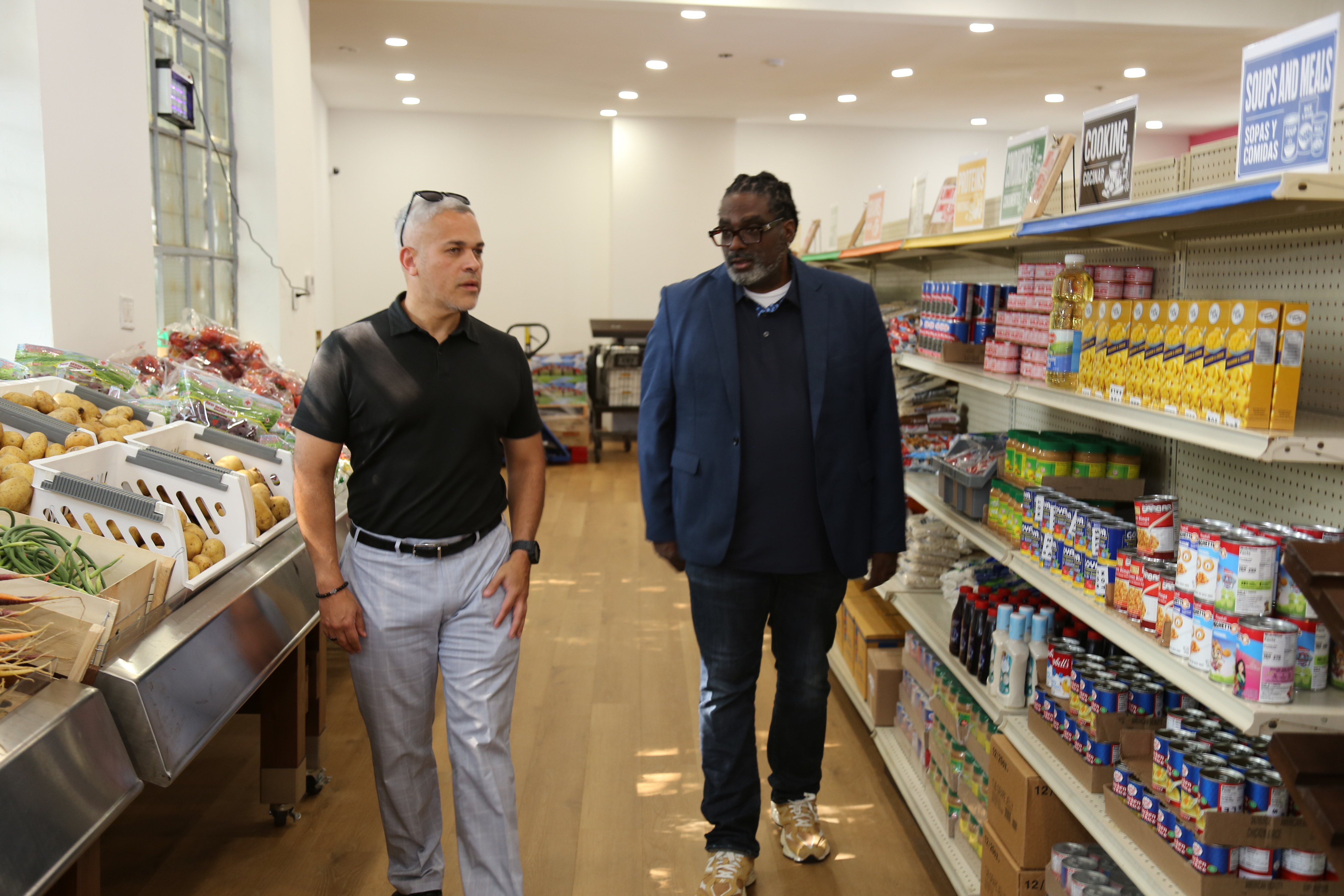 United Community Corporation’s executive director Craig Mainor (right) and City Councilmember Anibal Ramos walk through the newly opened grocery store-style food pantry in Newark’s West Ward neighborhood.