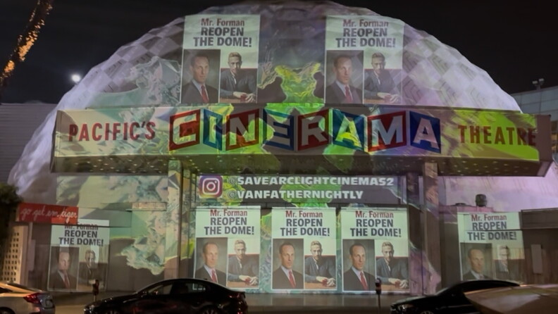 Images of two men and the words "reopen the dome" are projected onto a white domed building.